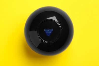 Photo of Magic eight ball with prediction Prospect Good on yellow background, top view