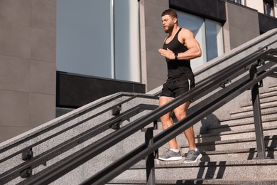 Photo of Man running down stairs outdoors on sunny day. Space for text