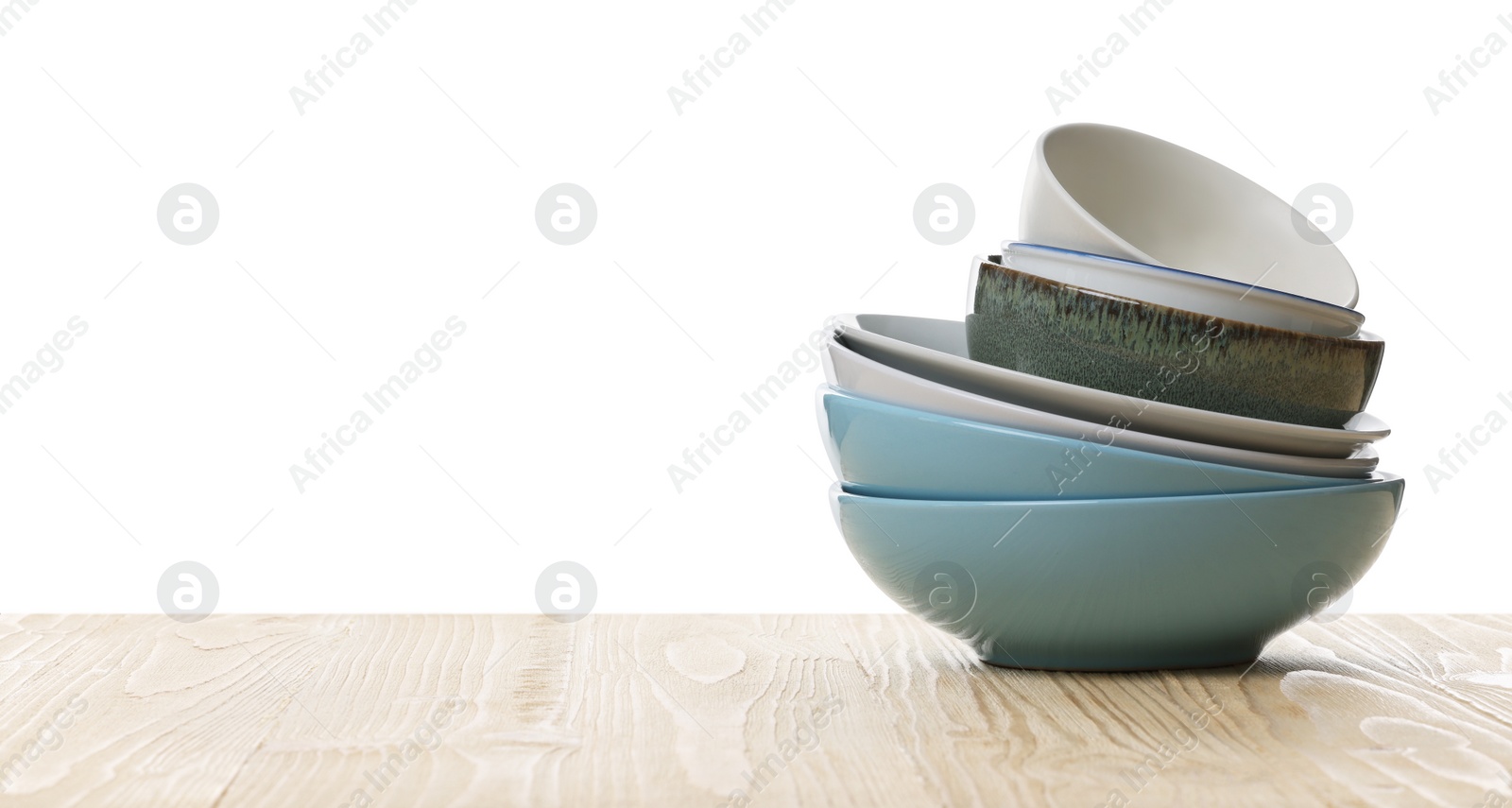 Photo of Set of clean color bowls on wooden table against white background