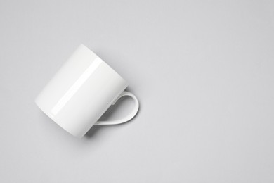 Photo of One white ceramic mug on light background, top view and space for text
