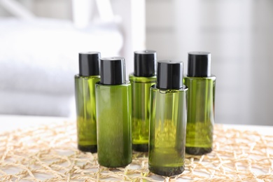 Mini bottles with cosmetic products on wicker mat indoors