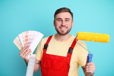 Photo of Male decorator with palette and roller on color background