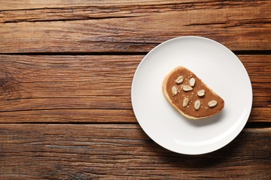 Photo of Toast with tasty nut butter and peanuts on wooden table, top view. Space for text