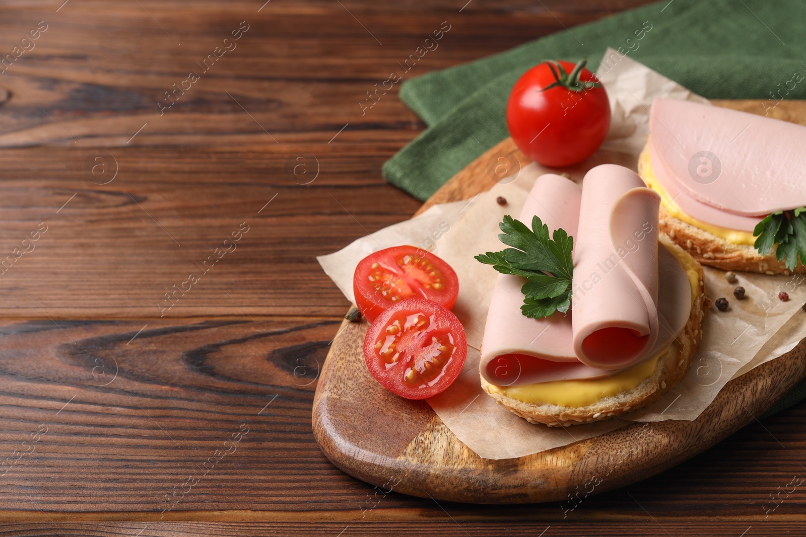 Photo of Delicious sandwiches with boiled sausage, cheese and tomatoes on wooden table, space for text