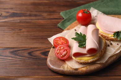 Delicious sandwiches with boiled sausage, cheese and tomatoes on wooden table, space for text