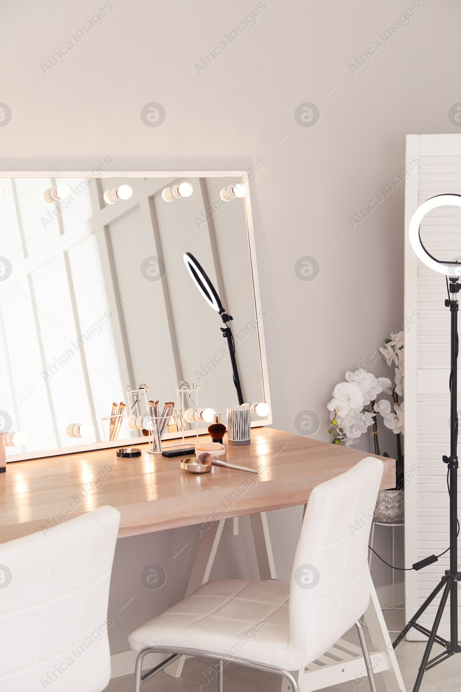 Photo of Modern mirror with light bulbs on dressing table in makeup room