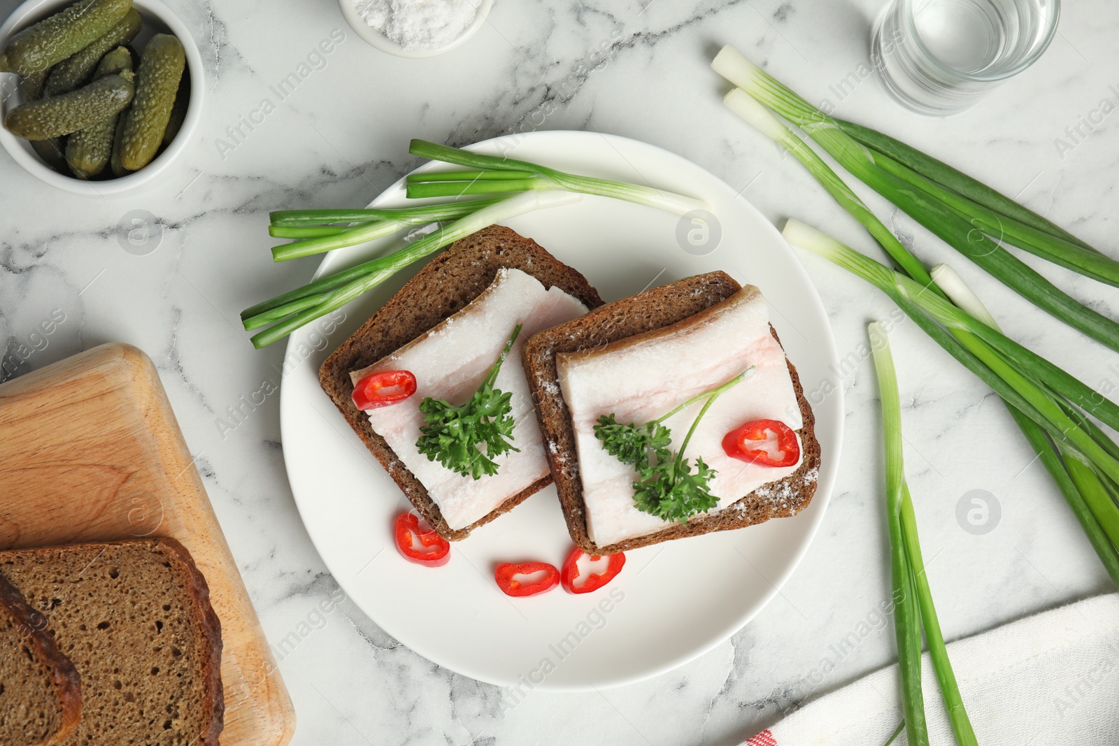 Photo of Plate with pork fatback sandwiches served on marble background, flat lay