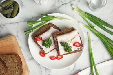 Photo of Plate with pork fatback sandwiches served on marble background, flat lay