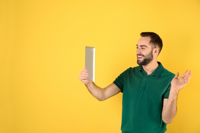 Photo of Man using tablet for video chat on color background. Space for text