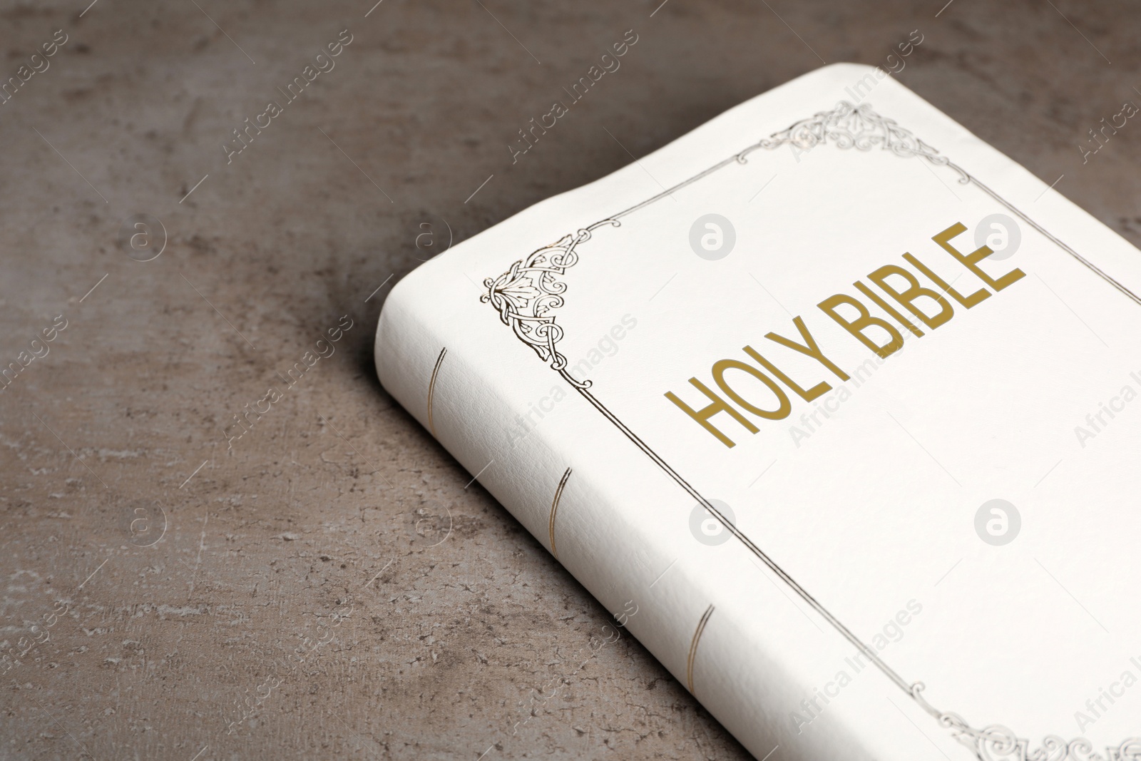 Photo of Bible with white cover on light grey table, closeup