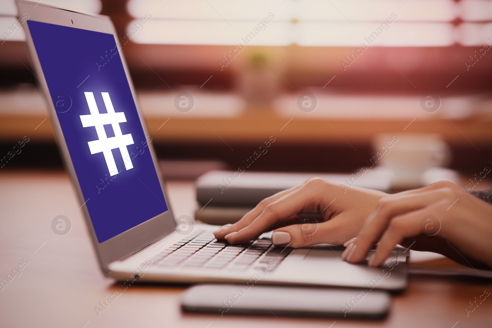 Image of Woman using modern laptop with hashtag symbol on screen at table, closeup