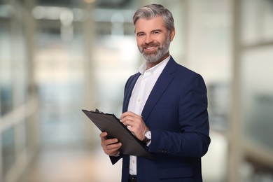 Successful lawyer with clipboard on blurred background