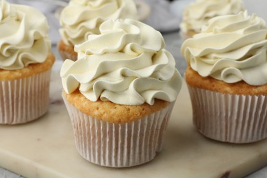 Tasty cupcakes with vanilla cream on table, closeup