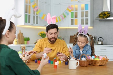 Family painting Easter eggs at table in kitchen