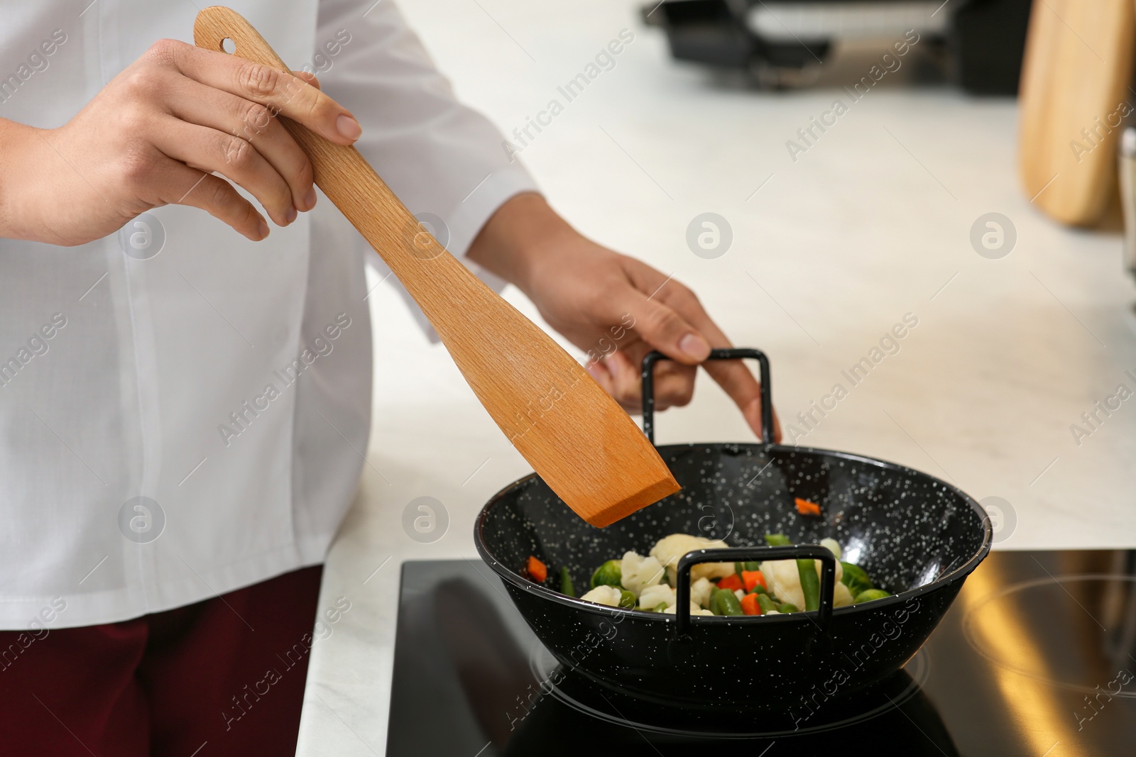 Photo of Professional chef stiring delicious dish in kitchen, closeup