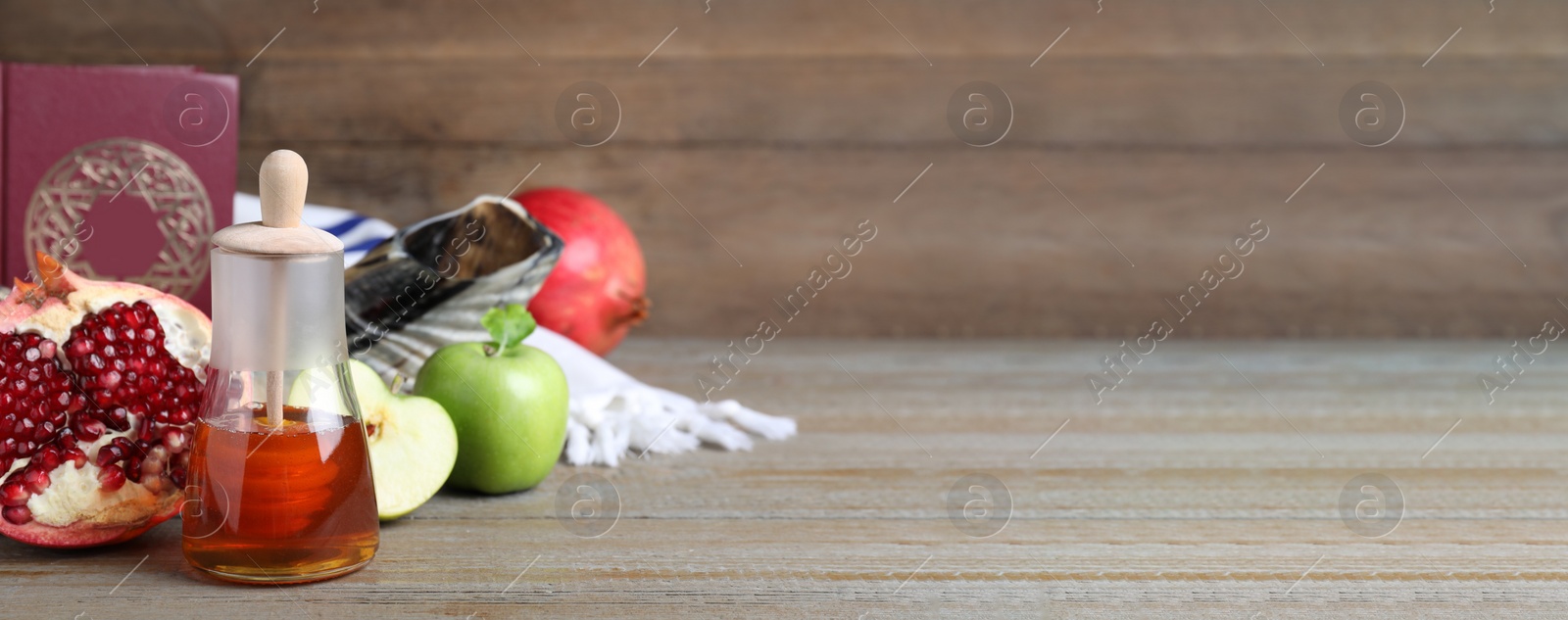 Image of Honey, pomegranate, apples, shofar and Torah on wooden table, banner design with space for text. Rosh Hashana holiday