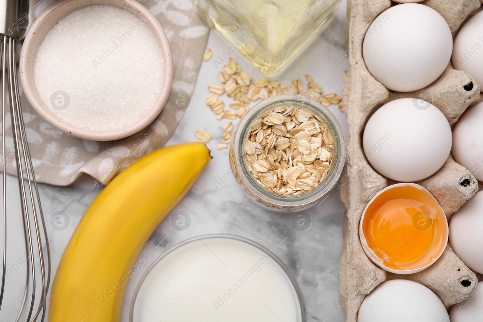 Photo of Different ingredients for cooking tasty oatmeal pancakes on white marble table, flat lay