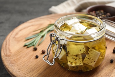 Jar with feta cheese marinated in oil on table. Pickled food