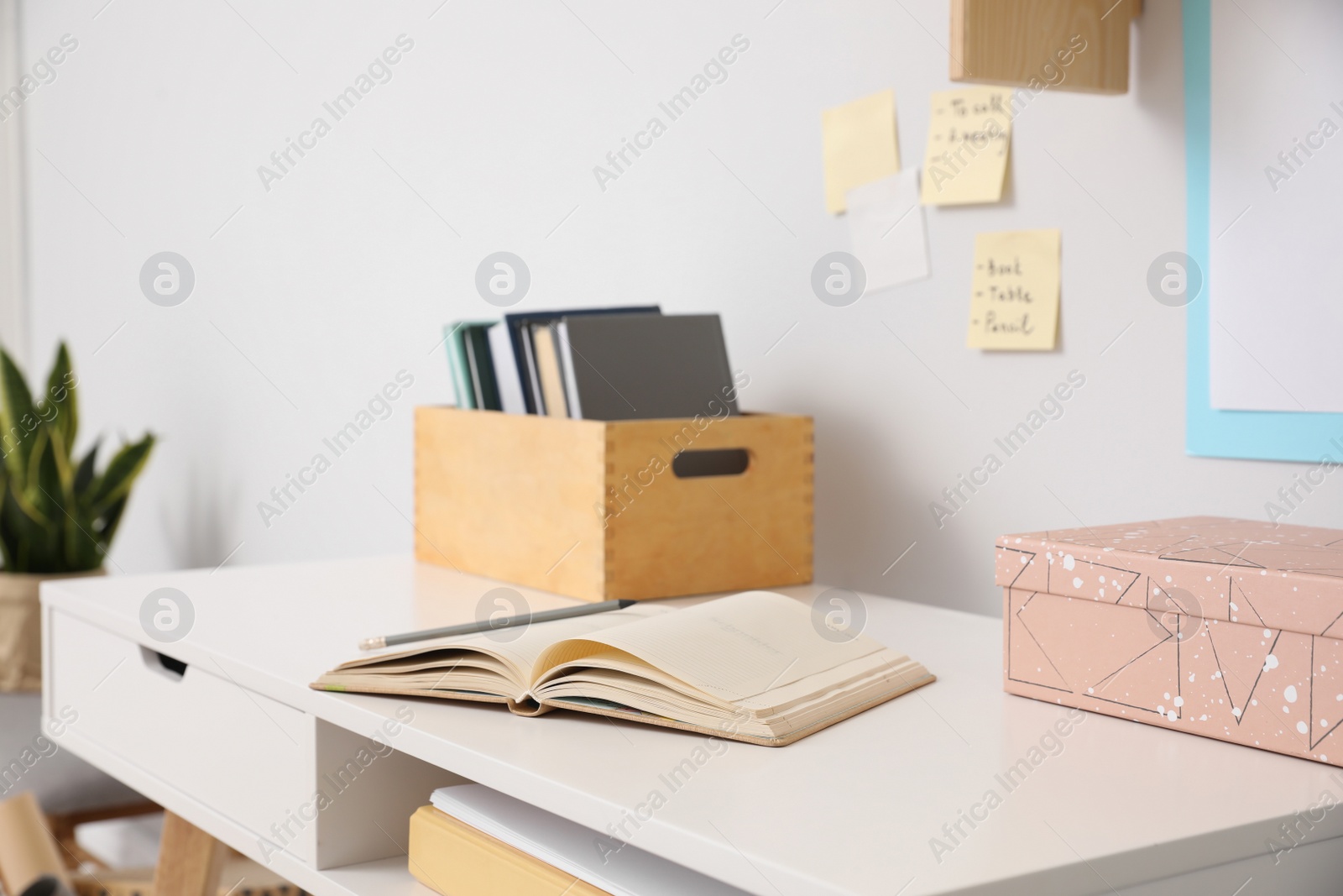 Photo of Comfortable workplace with open notebook near white wall in room