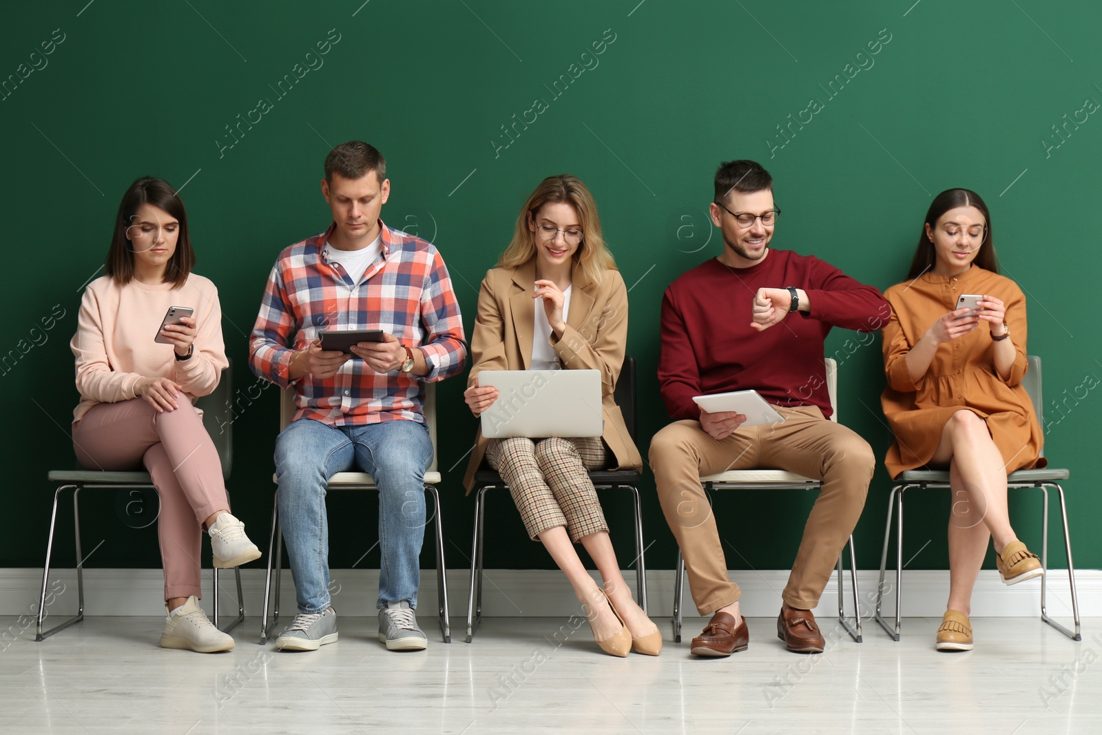 Photo of People waiting for job interview near green wall indoors