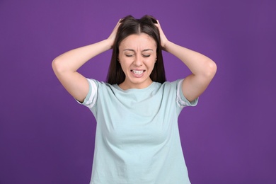 Photo of Portrait of stressed young woman on purple background