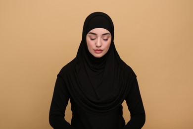 Portrait of Muslim woman in hijab on beige background