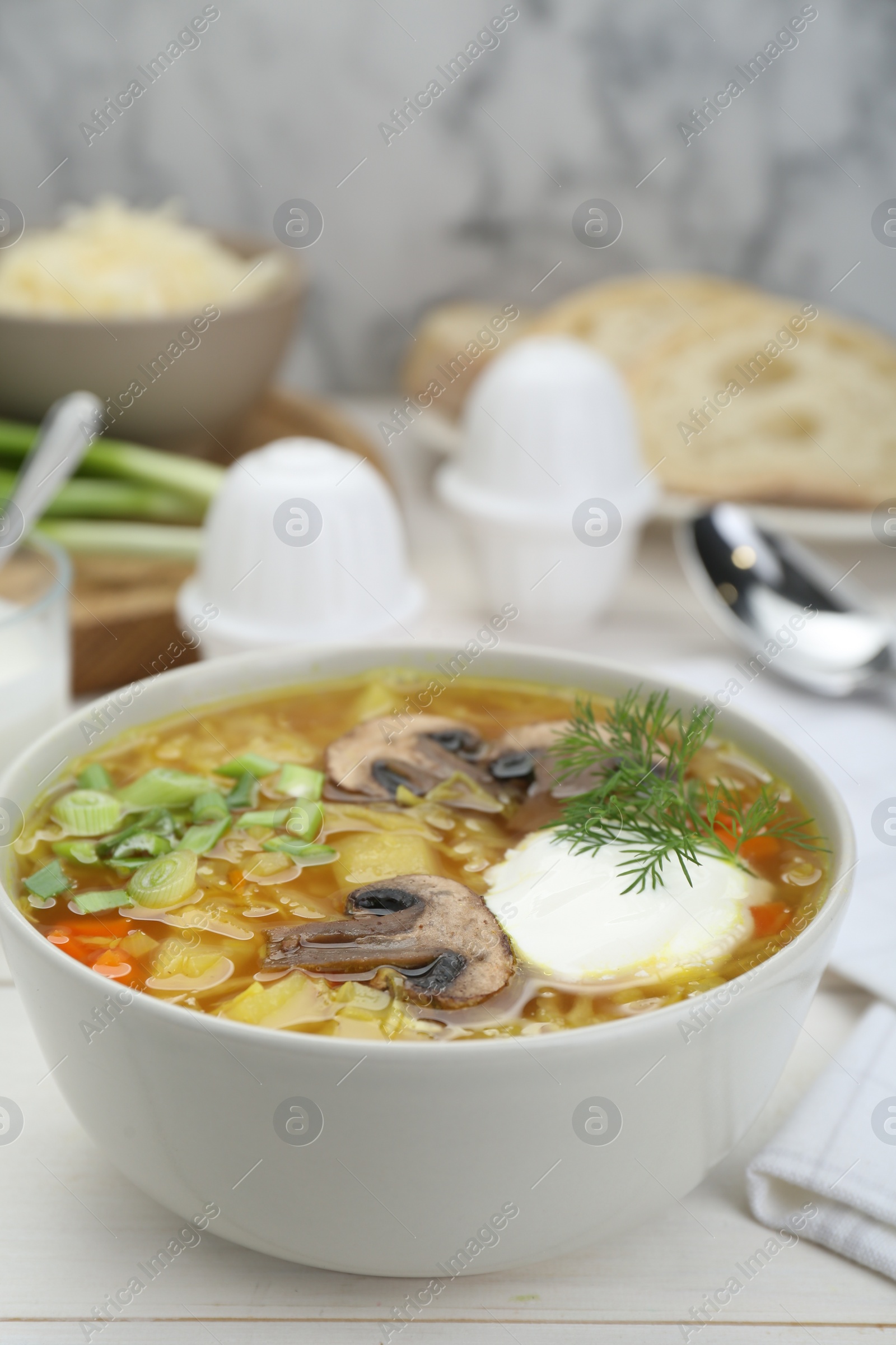 Photo of Delicious sauerkraut soup with mushrooms, dill and sour cream served on white table