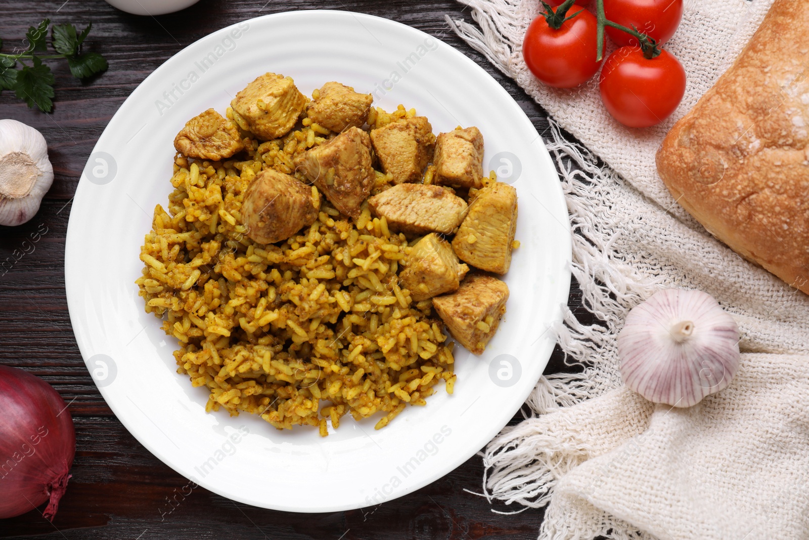 Photo of Delicious rice with chicken served on wooden table, flat lay