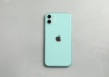 Photo of MYKOLAIV, UKRAINE - JULY 9, 2020: New modern Iphone 11 Green on grey table, top view