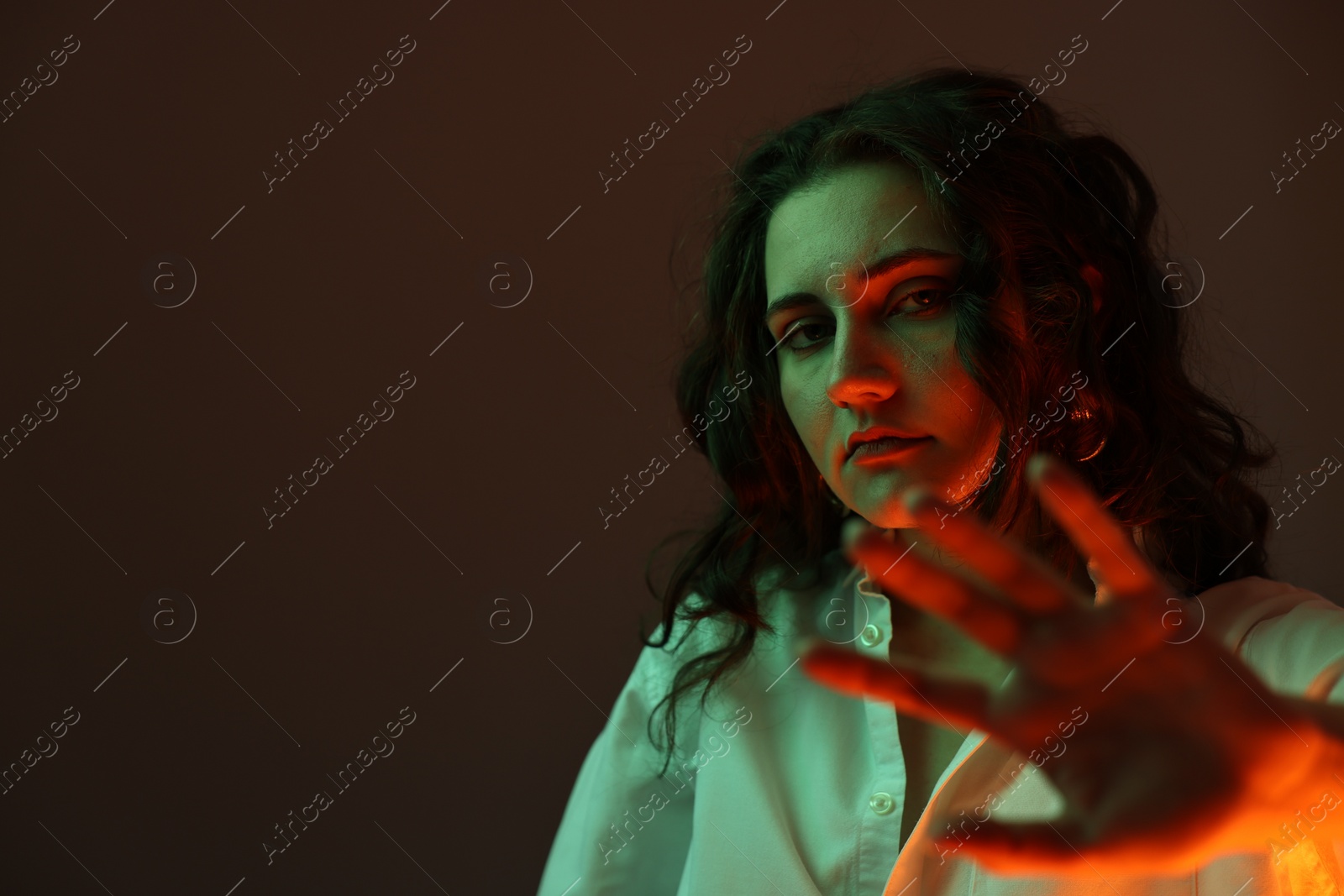 Photo of Portrait of beautiful young woman on color background with neon lights, space for text