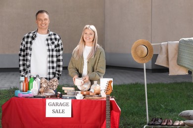 Photo of Happy family selling different items on garage sale in yard