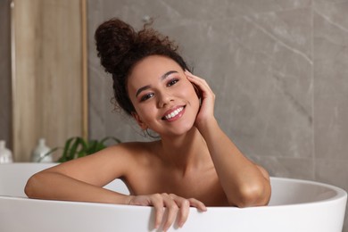 Photo of Beautiful African American woman taking bath indoors
