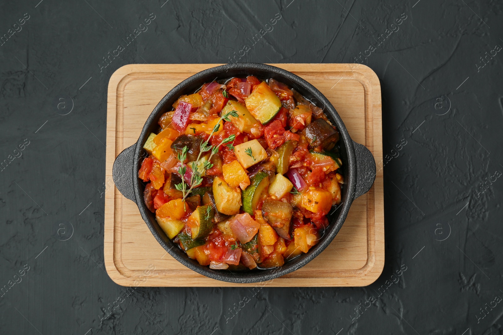 Photo of Dish with tasty ratatouille on black table, top view