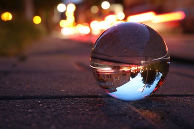 Beautiful city street, overturned reflection. Crystal ball on asphalt road at night. Space for text
