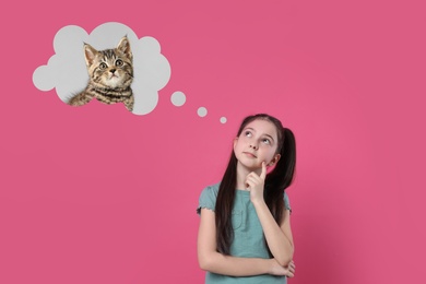 Little girl on pink background dreaming about cute kitten