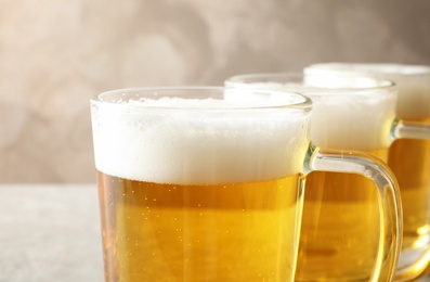 Photo of Glass mugs of cold tasty beer on table, closeup