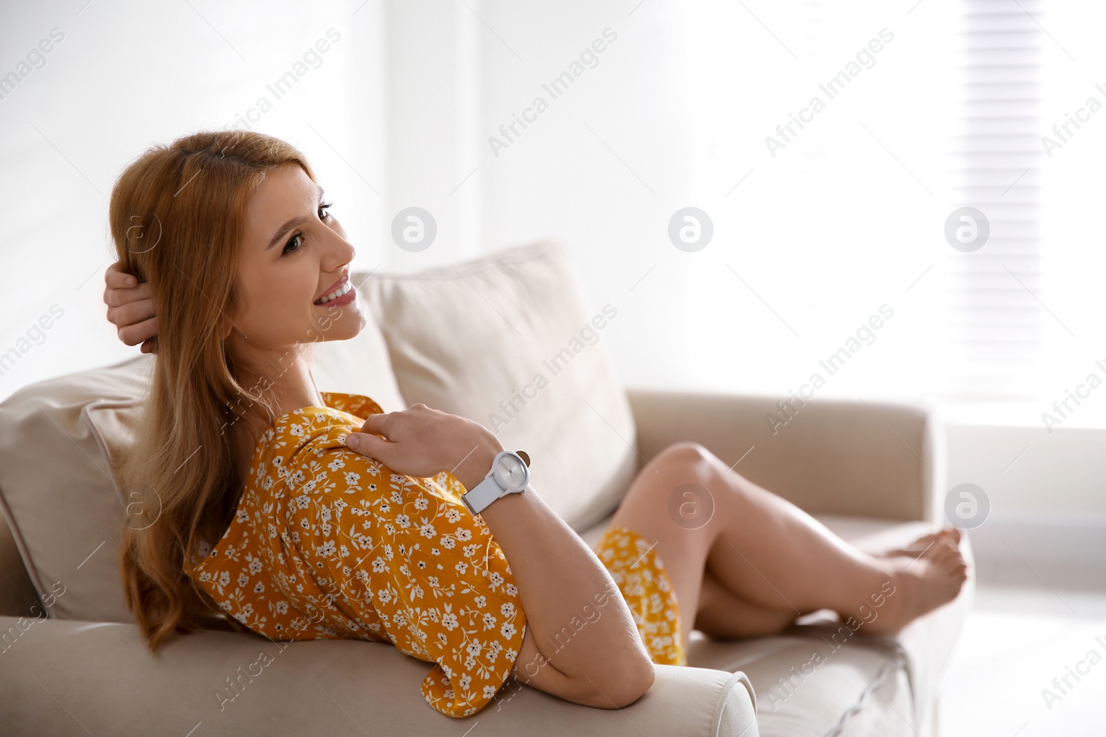 Photo of Young woman relaxing on couch near window at home. Space for text