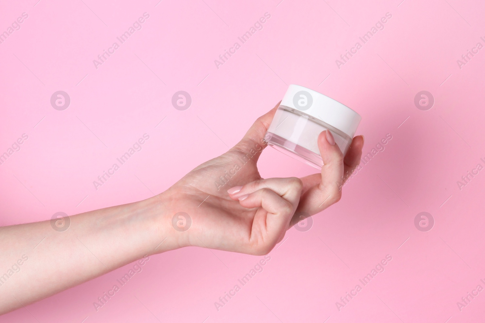 Photo of Woman holding jar of cream on pink background, closeup