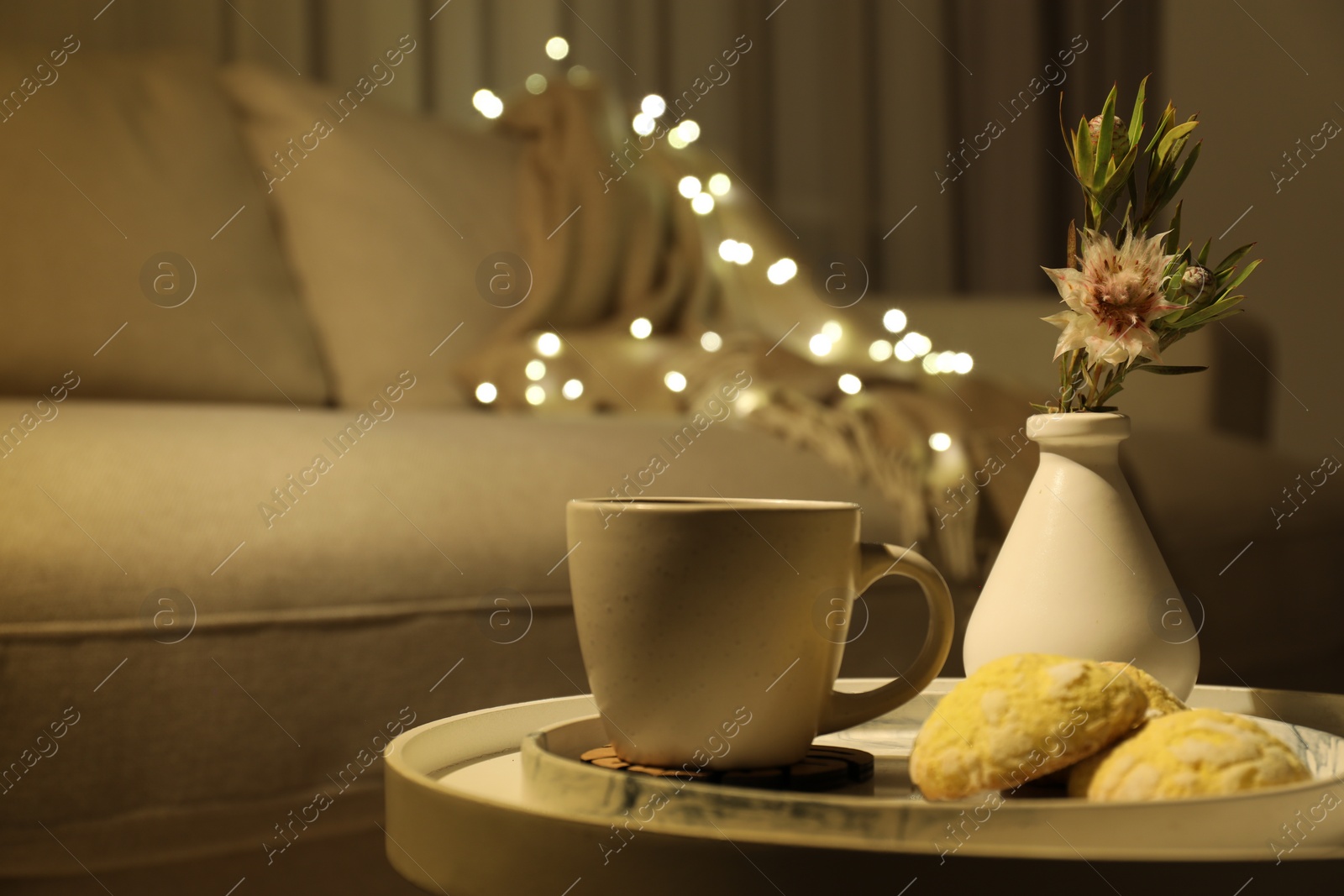 Photo of Cup of drink, cookies and vase of flowers on table indoors, space for text