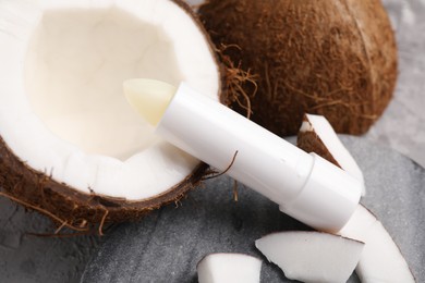 Photo of Lip balm and coconut on grey table, closeup