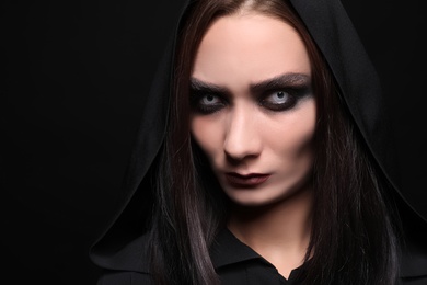 Photo of Mysterious witch with spooky eyes on black background, closeup