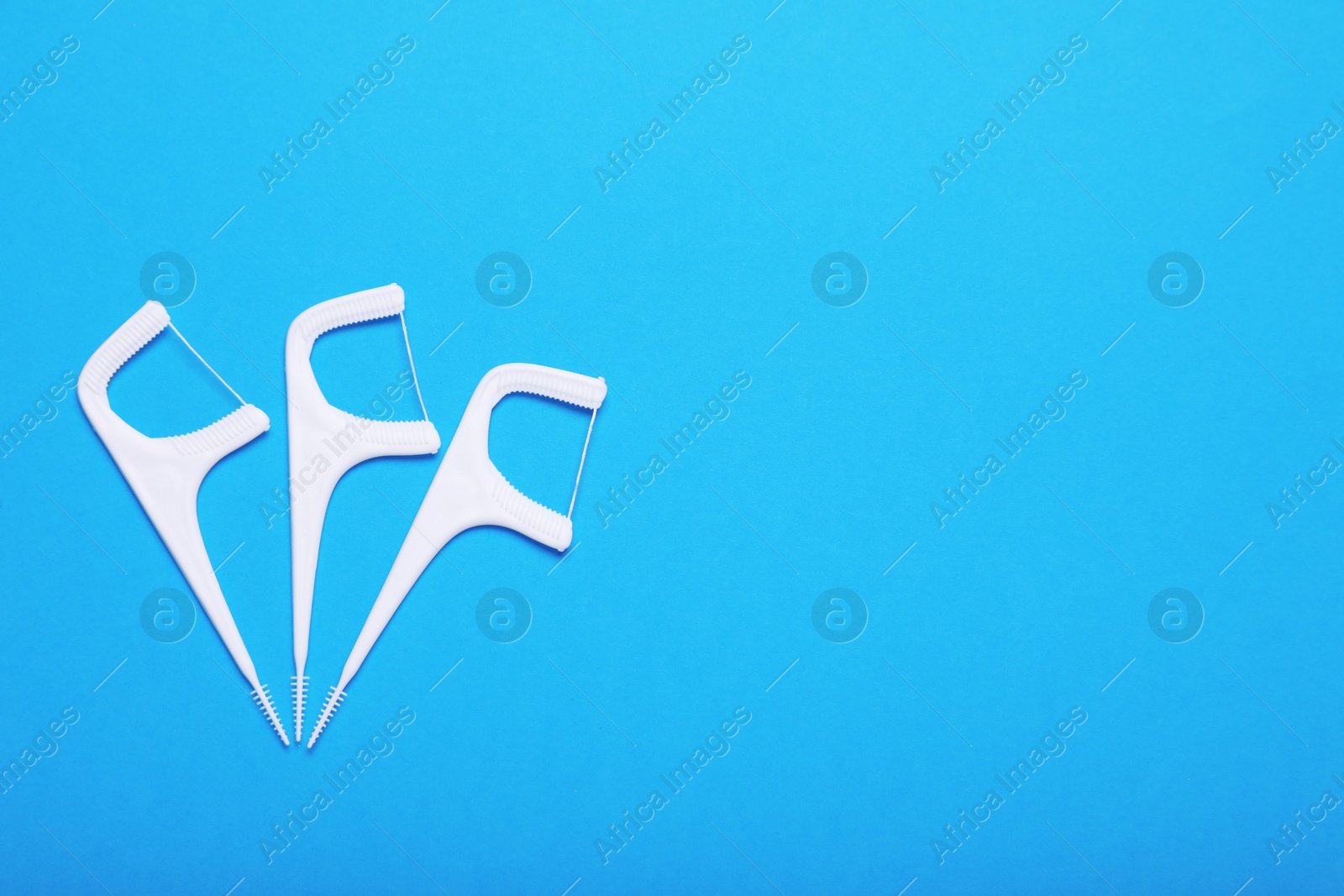 Photo of Dental flossers on light blue background, flat lay. Space for text
