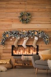 Photo of Decorative fireplace with Christmas stockings in festive room interior