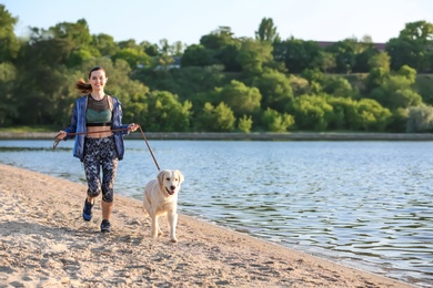 Young woman with her dog together on beach. Pet care