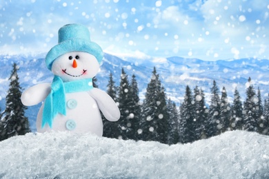 Image of Cute toy snowman in winter forest. Space for text