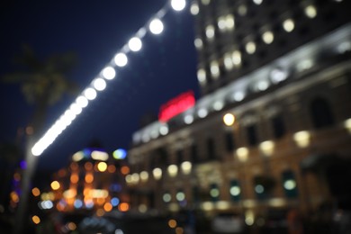 Blurred view of beautiful cityscape with glowing streetlights and illuminated building at night