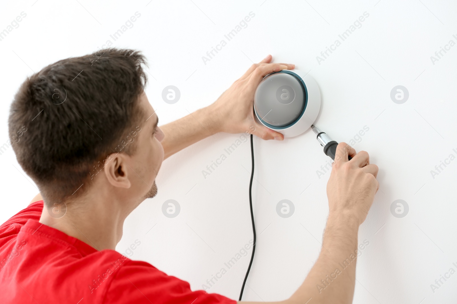 Photo of Technician installing CCTV camera on wall indoors