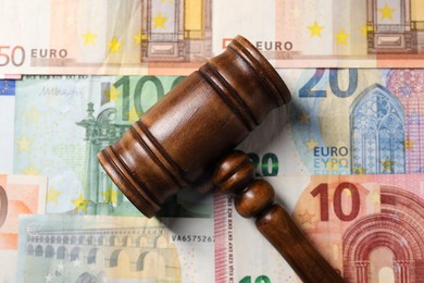 Photo of Tax law. Wooden gavel on euro banknotes, top view