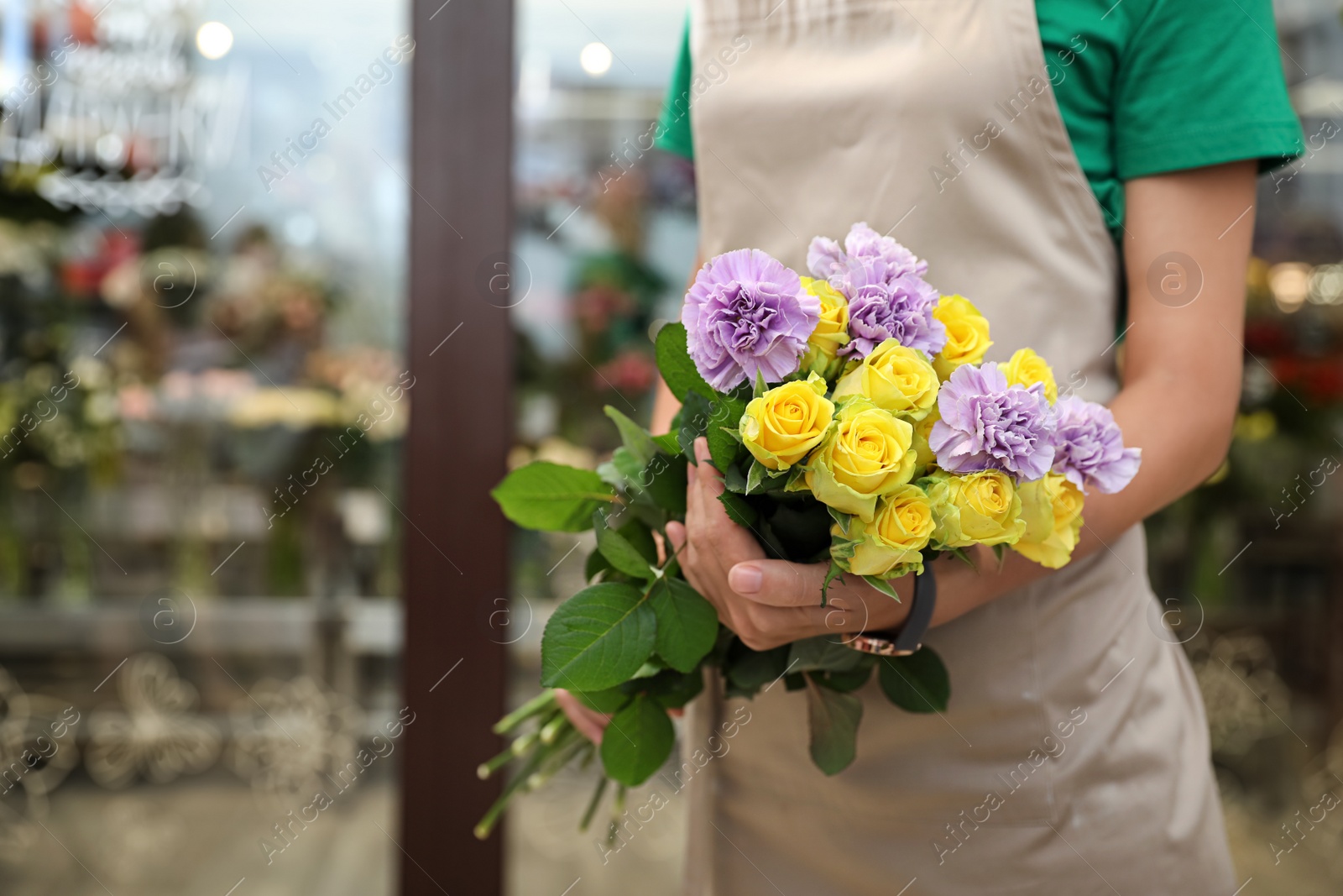 Photo of Female florist holding beautiful bouquet in flower shop, closeup