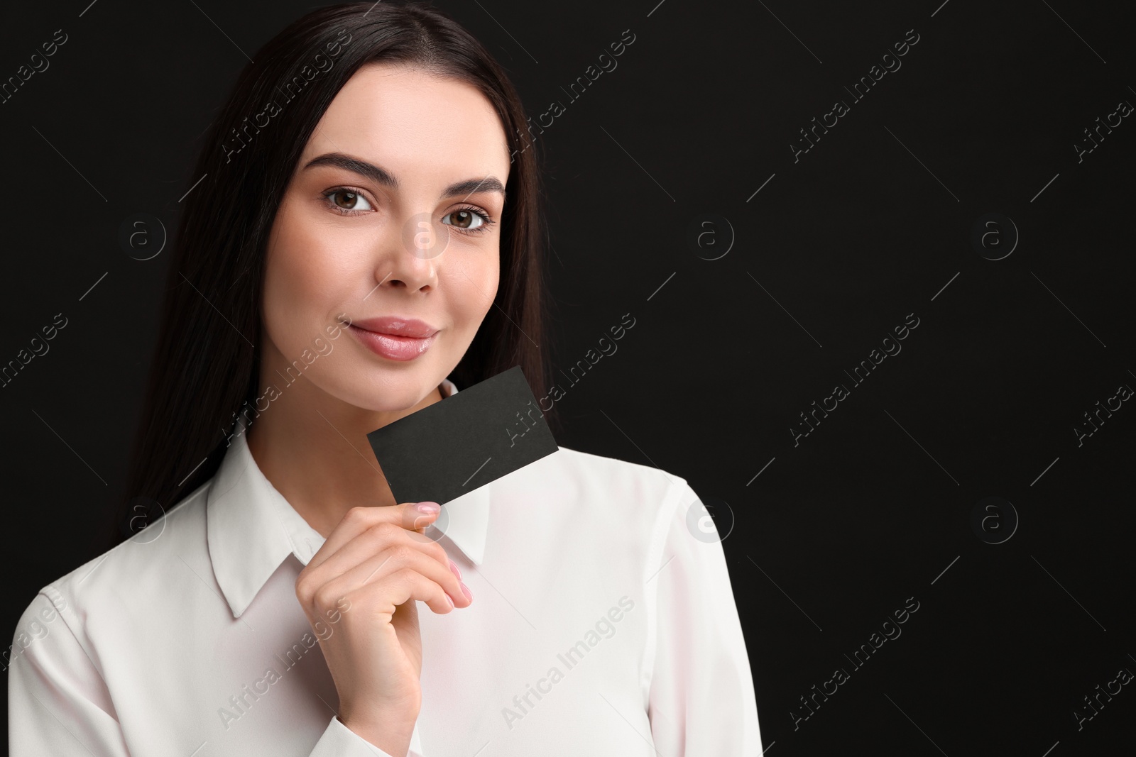 Photo of Woman holding blank business card on black background. Space for text